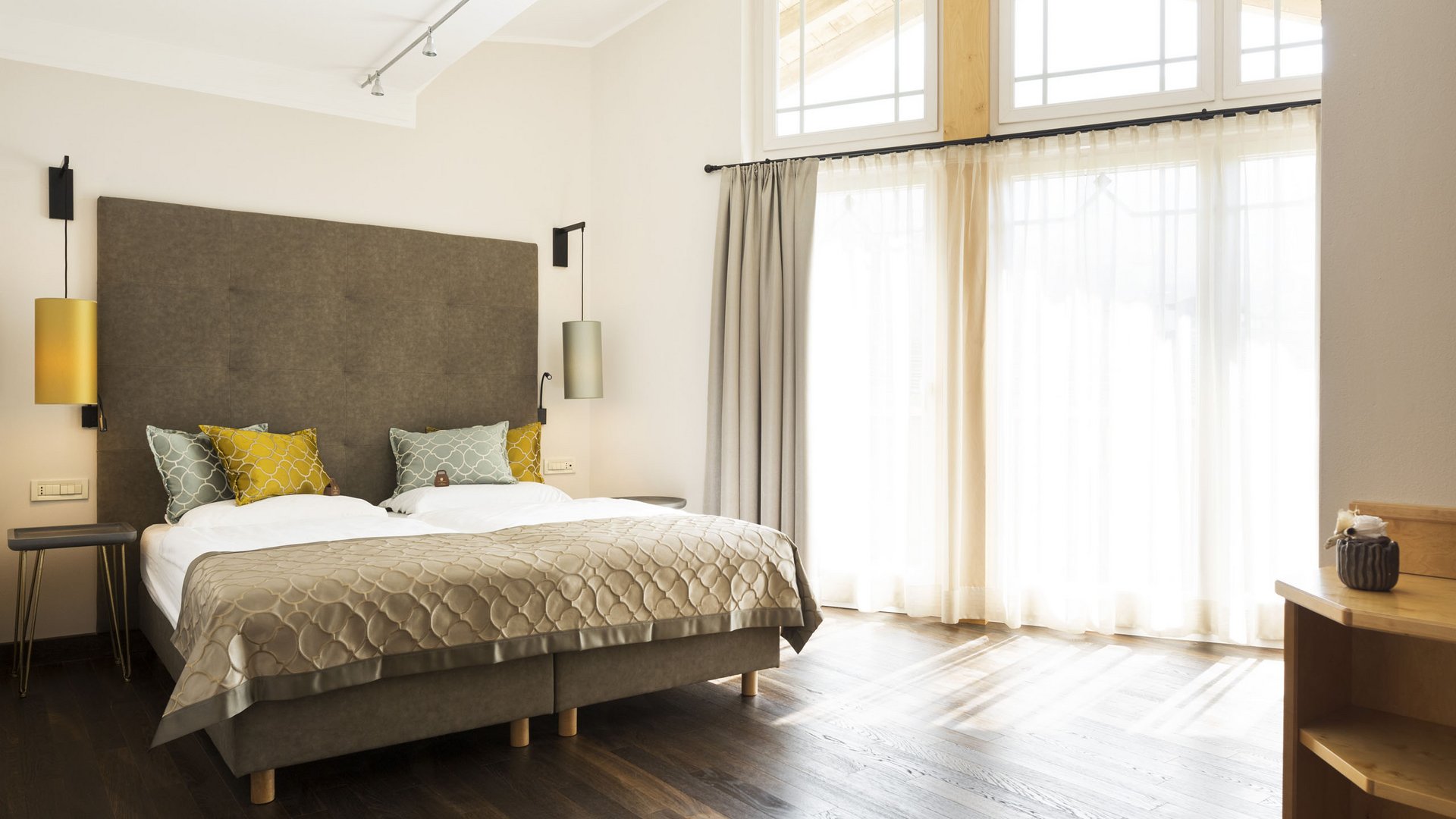 Il vostro alloggio a Merano con vista panoramica: il Burggräflerhof Camera da letto luminosa con letto matrimoniale, cuscini e grandi finestre con tende