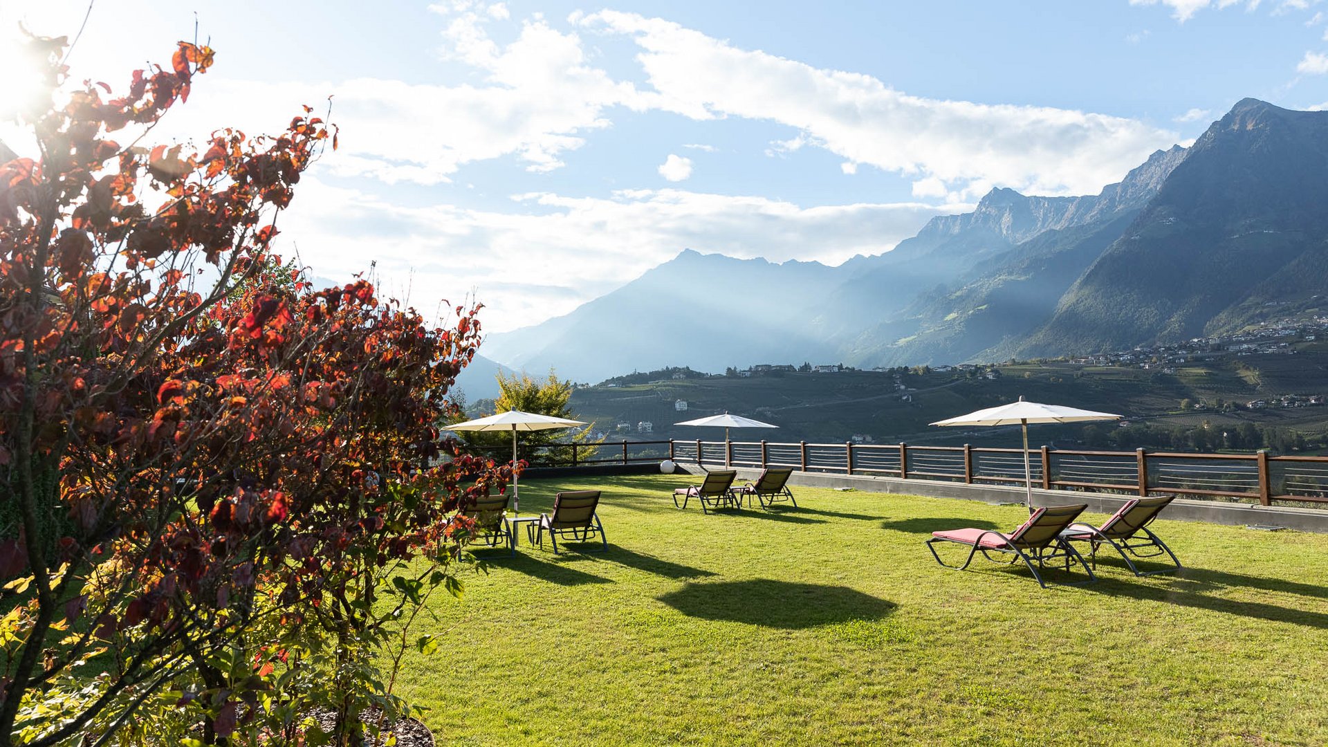Burggräflerhof, il vostro hotel con giardino panoramico in Alto Adige Prato verde con sdraio e ombrelloni davanti a montagne sotto cielo soleggiato
