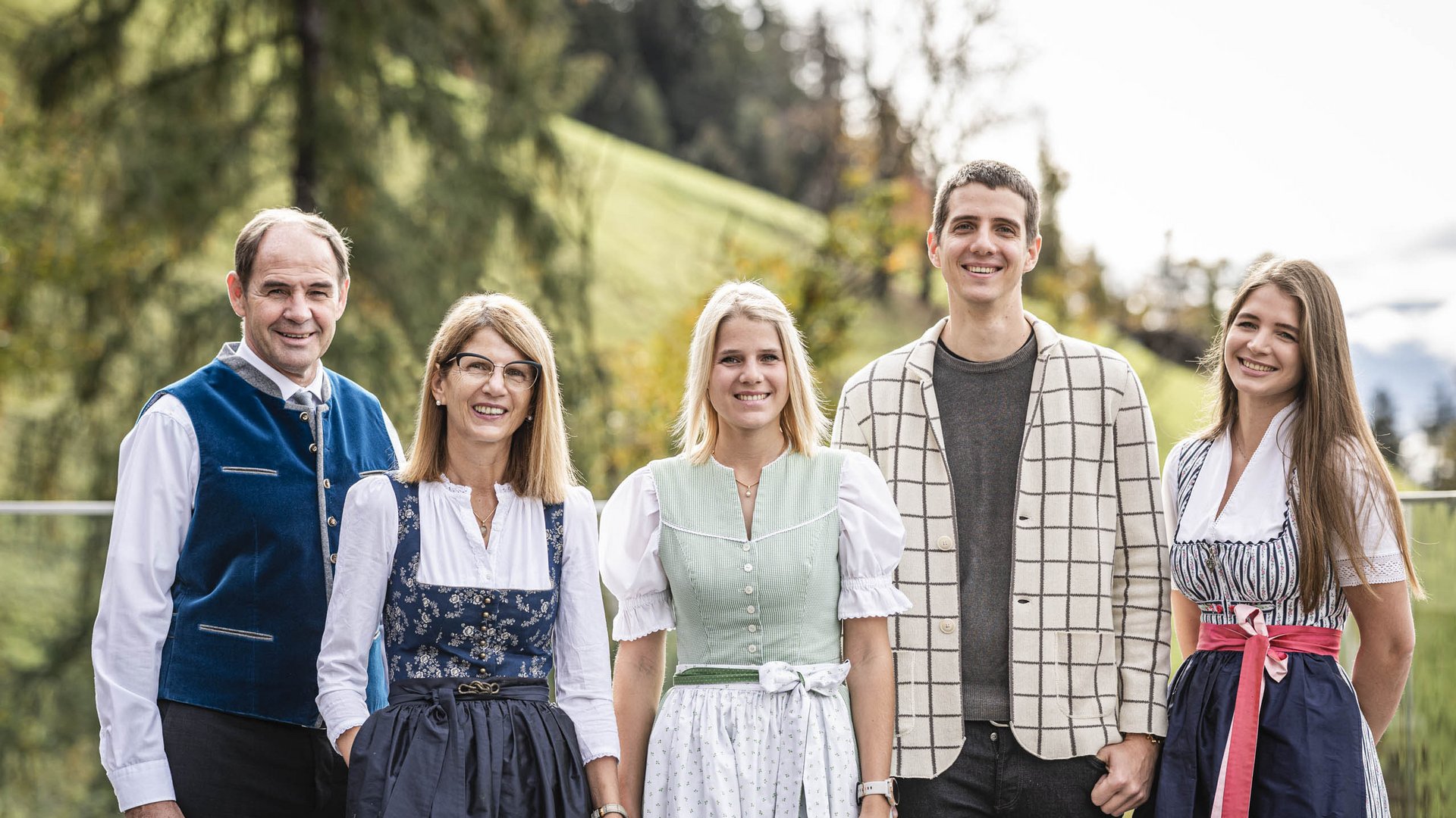 Cinque persone in abito tradizionale con paesaggio rurale sullo sfondo