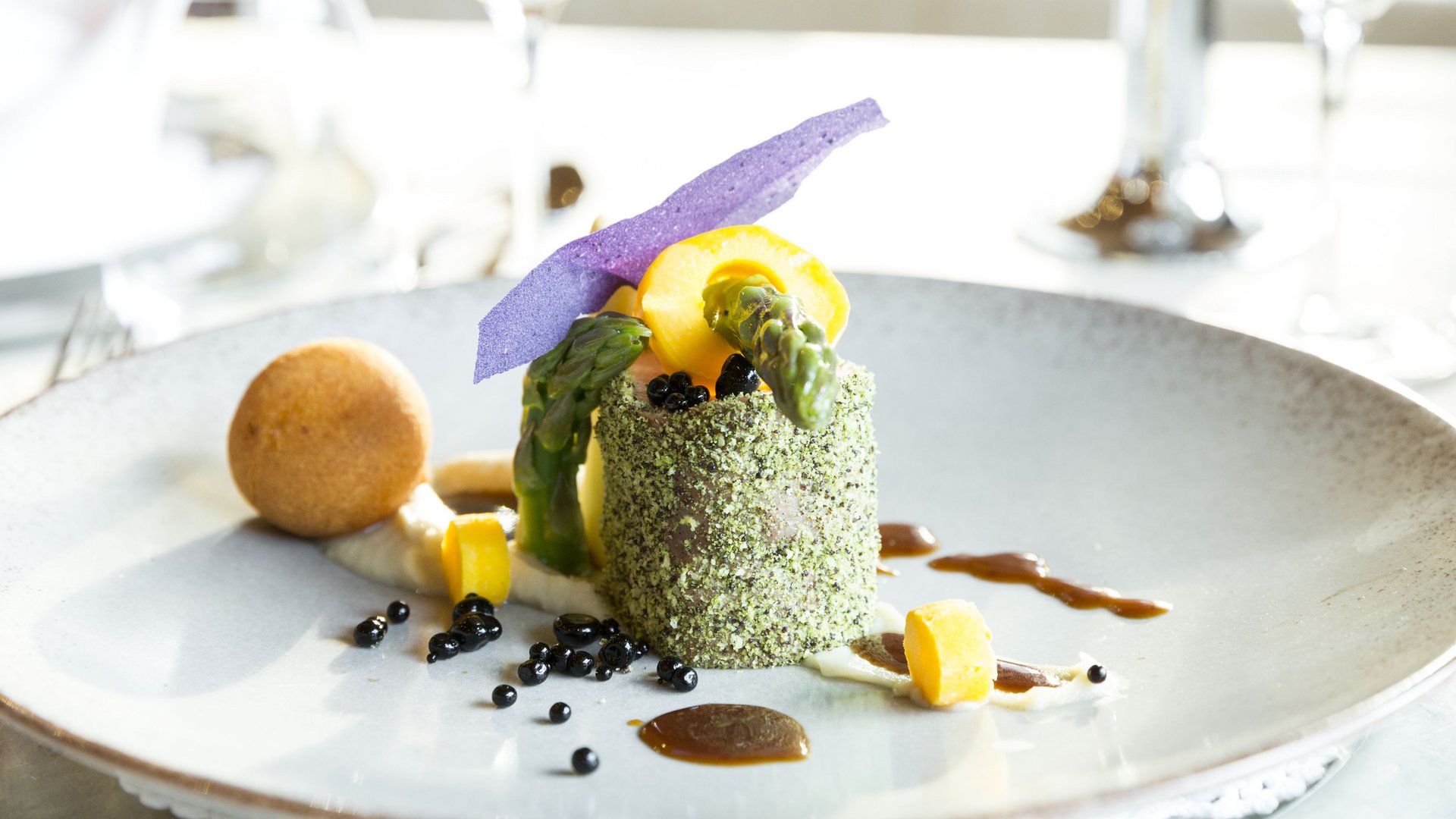 Piatto gourmet con rivestimento verde, asparagi e decorazioni colorate su piatto bianco